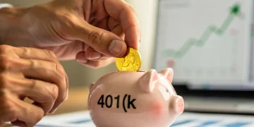Hands placing coin into 401(k) piggy bank, symbolizing retirement savings growth in 2026.
